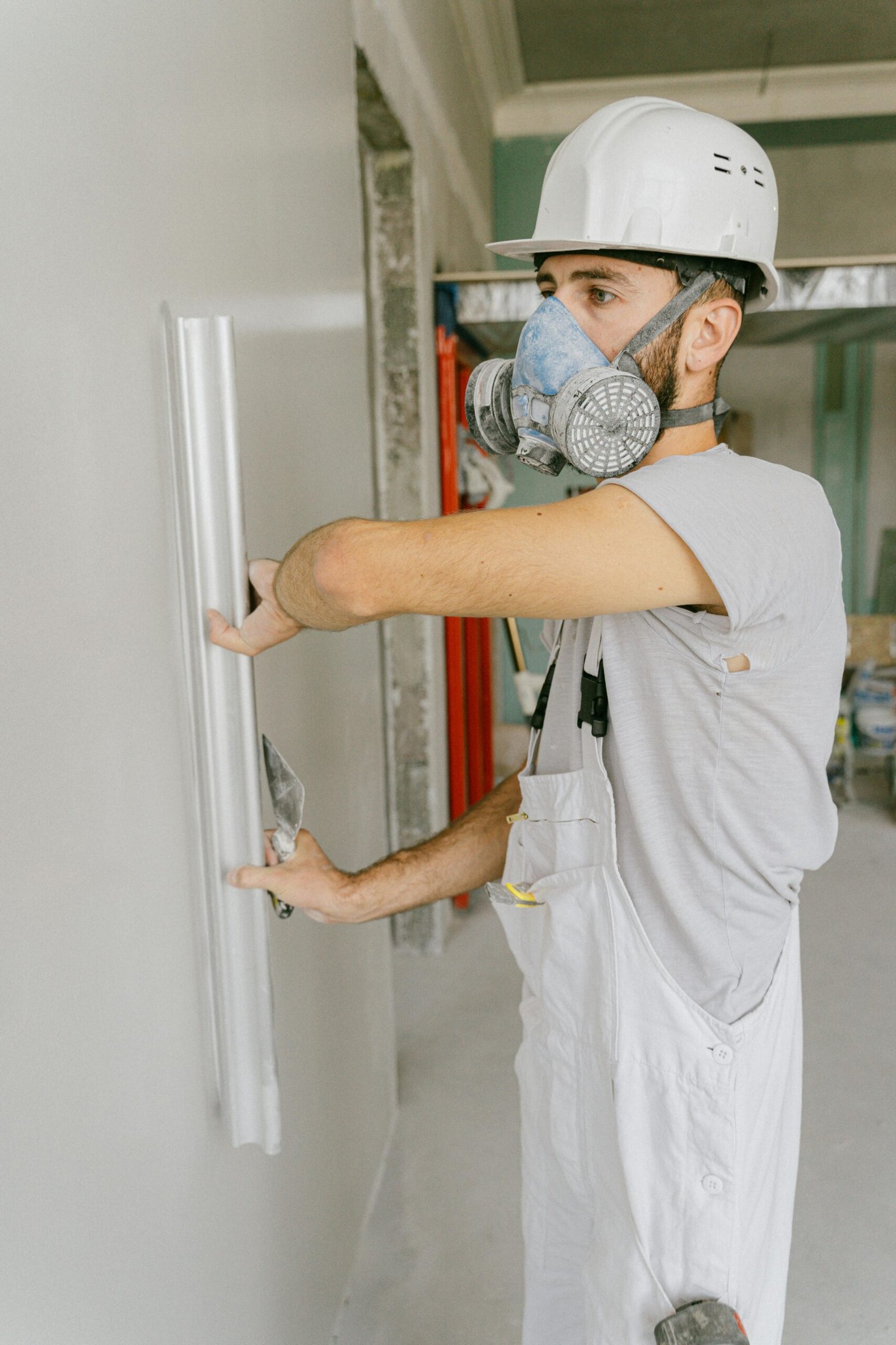 Construction worker smoothing wall with trowel during renovation project.